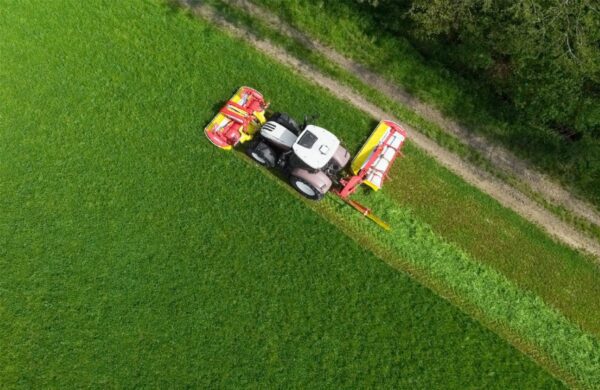 An aerial view of a POTTINGER NOVADISC 262 rear disc mower on a green field.