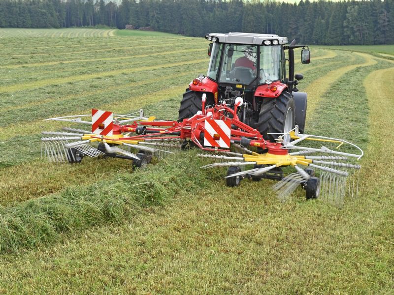 A POTTINGER TOP 612 MOUNTED RAKE being pulled by a tractor in a field.