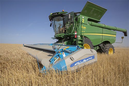 A green Shelbourne Reynolds combine harvester in a field.